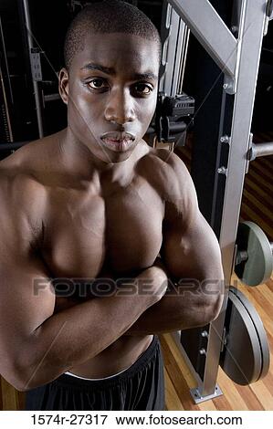Portrait of a shirtless young man standing in the gym with arms crossed View Large Photo Image Stock Photo - Portrait of a shirtless young man standing in the gym with arms crossed. Fotosearch