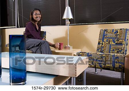 Portrait of a smiling businesswoman holding a tea cup in an office View Large Photo Image Stock Image - Portrait of a smiling businesswoman holding a tea cup in an office. Fotosearch