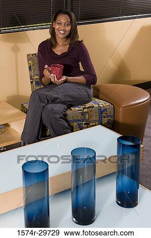 Stock Photo - Portrait of a smiling businesswoman holding tea cup in an office. Fotosearch