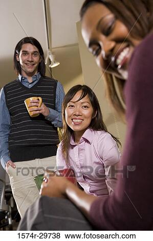 Portrait of a smiling businesswoman with colleagues holding tea cup in an office View Large Photo Image Stock Photo - Portrait of a smiling businesswoman with colleagues holding tea cup in an office. Fotosearch
