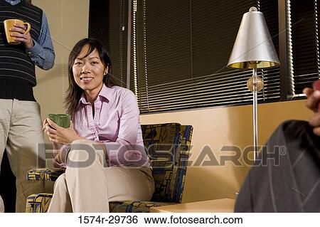 Portrait of a smiling businesswoman with colleague holding tea cup in an office View Large Photo Image Stock Photograph - Portrait of a smiling businesswoman with colleague holding tea cup in an office. Fotosearch