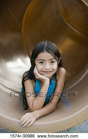 Portrait of a smiling girl lying on tunnel slide with hand on chin View Large Photo Image Stock Photograph - Portrait of a smiling girl lying on tunnel slide with hand on chin. Fotosearch