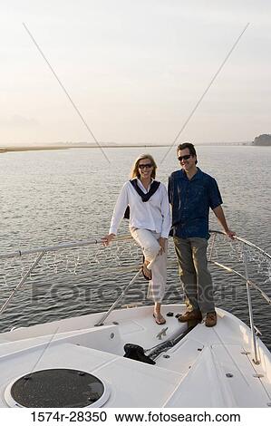 Portrait of a smiling mid adult couple standing at bow of a boat View Large Photo Image Stock Image - Portrait of a smiling mid adult couple standing at bow of a boat. Fotosearch