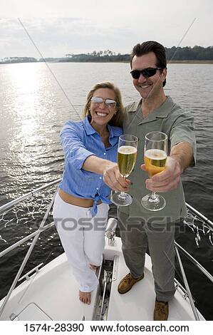 Portrait of a smiling mid adult couple standing with glass of champagne at bow of a boat View Large Photo Image Stock Image - Portrait of a smiling mid adult couple standing with glass of champagne at bow of a boat. Fotosearch