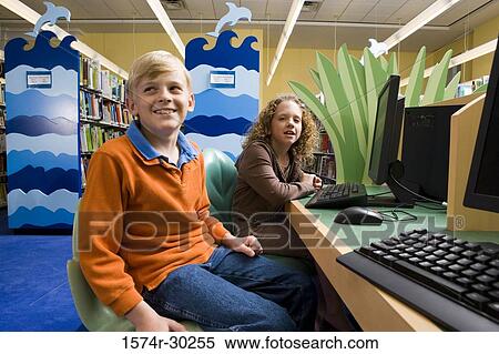 Portrait of a smiling schoolboy and girl sitting with computers in the library View Large Photo Image Stock Photography - Portrait of a smiling schoolboy and girl sitting with computers in the library. Fotosearch