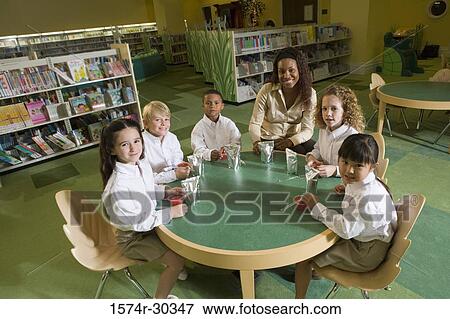 Stock Photo - Portrait of a smiling teacher sitting with students at breakfast in the library. Fotosearch