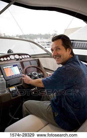 Portrait of a smiling young man steering boat View Large Photo Image Stock Photo - Portrait of a smiling young man steering boat. Fotosearch