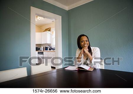 Portrait of a smiling young woman sitting by table View Large Photo Image Stock Photograph - Portrait of a smiling young woman sitting by table. Fotosearch