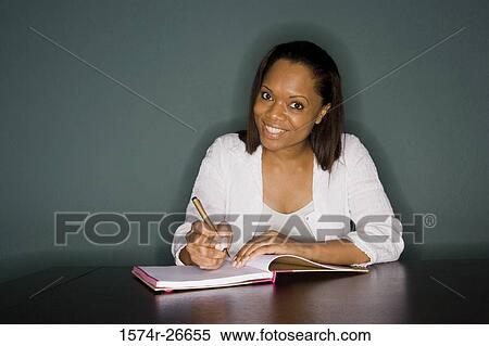 Portrait of a smiling young woman writing in a book View Large Photo Image Stock Photography - Portrait of a smiling young woman writing in a book. Fotosearch