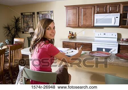 Portrait of a teenage girl studying on kitchen counter in kitchen View Large Photo Image Stock Photo - Portrait of a teenage girl studying on kitchen counter in kitchen. Fotosearch
