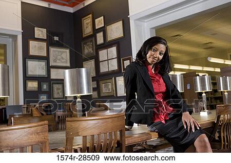 Portrait of a well-dressed businesswoman sitting on a conference table in an office View Large Photo Image Stock Photo - Portrait of a well-dressed businesswoman sitting on a conference table in an office. Fotosearch