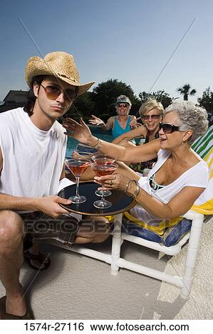 Portrait of a young man holding tray of drinks by senior women View Large Photo Image Stock Photograph - Portrait of a young man holding tray of drinks by senior women. Fotosearch