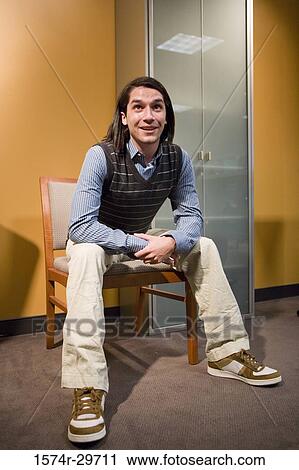 Stock Image - Portrait of a young man sitting on a chair. Fotosearch