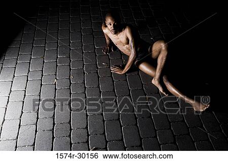 Stock Photograph - Portrait of a young man sitting on the tiled floor. Fotosearch