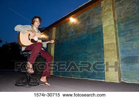 Portrait of a young man sitting with guitar View Large Photo Image Stock Photography - Portrait of a young man sitting with guitar. Fotosearch