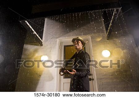 Portrait of a young man standing in front of the door and holding an umbrella View Large Photo Image Stock Image - Portrait of a young man standing in front of the door and holding an umbrella. Fotosearch