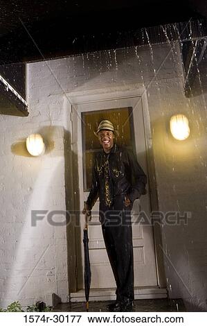 Portrait of a young man standing in front of the door and holding an umbrella View Large Photo Image Stock Photo - Portrait of a young man standing in front of the door and holding an umbrella. Fotosearch