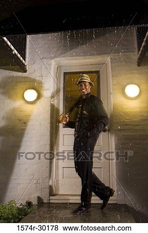 Portrait of a young man standing in front of the door and holding an umbrella View Large Photo Image Stock Photo - Portrait of a young man standing in front of the door and holding an umbrella. Fotosearch