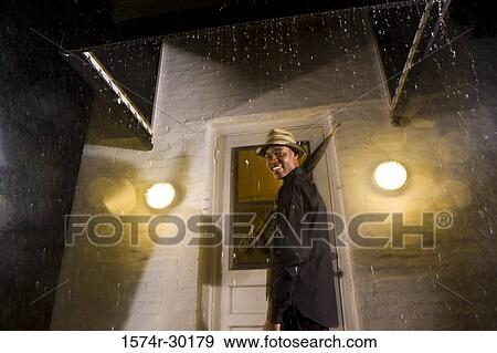 Portrait of a young man standing in front of the door and holding an umbrella View Large Photo Image Stock Photo - Portrait of a young man standing in front of the door and holding an umbrella. Fotosearch