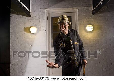 Stock Photography - Portrait of a young man standing in front of the door and holding an umbrella. Fotosearch