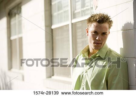 Stock Photo - Portrait of a young man staring by wall. Fotosearch
