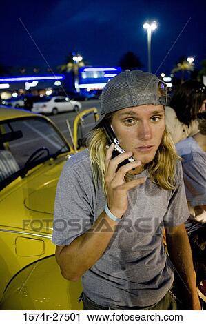 Portrait of a young man using a mobile phone by a car at the parking area View Large Photo Image Stock Image - Portrait of a young man using a mobile phone by a car at the parking area. Fotosearch