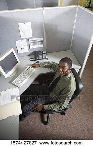 Portrait of a young man using headset by a desk in an office View Large Photo Image Stock Photo - Portrait of a young man using headset by a desk in an office. Fotosearch
