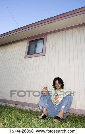 Portrait of a young man with curly hair sitting on grass View Large Photo Image Stock Photo - Portrait of a young man with curly hair sitting on grass. Fotosearch