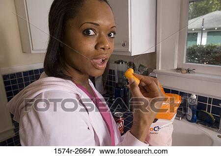 Portrait of a young woman eating snacks in the kitchen View Large Photo Image Stock Photo - Portrait of a young woman eating snacks in the kitchen. Fotosearch