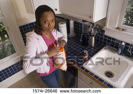 Portrait of a young woman holding a cheese packet in the kitchen View Large Photo Image Stock Photograph - Portrait of a young woman holding a cheese packet in the kitchen. Fotosearch