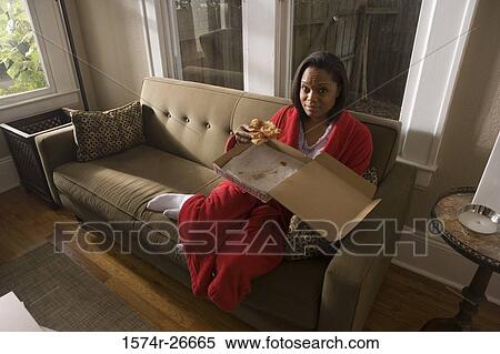 Portrait of a young woman in gown holding pizza on a sofa View Large Photo Image Stock Photography - Portrait of a young woman in gown holding pizza on a sofa. Fotosearch