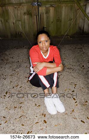 Portrait of a young woman in sports clothing sitting in front of a wooden door View Large Photo Image Stock Image - Portrait of a young woman in sports clothing sitting in front of a wooden door. Fotosearch