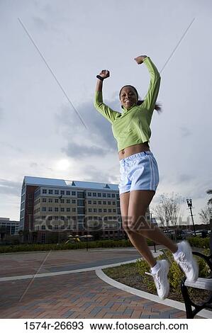 Portrait of a young woman in sports clothing jumping from bench View Large Photo Image Stock Image - Portrait of a young woman in sports clothing jumping from bench. Fotosearch