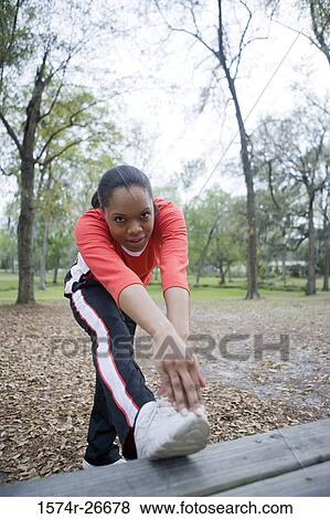 Portrait of a young woman in sports clothing stretching her leg on ground View Large Photo Image Stock Photo - Portrait of a young woman in sports clothing stretching her leg on ground. Fotosearch