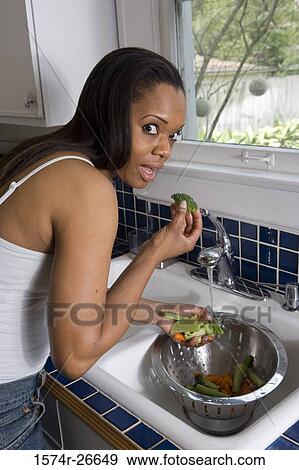 Stock Photo - Portrait of a young woman washing vegetables in a sink. Fotosearch