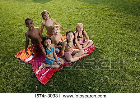 Stock Image - Portrait of boys and girls sitting on a towel. Fotosearch