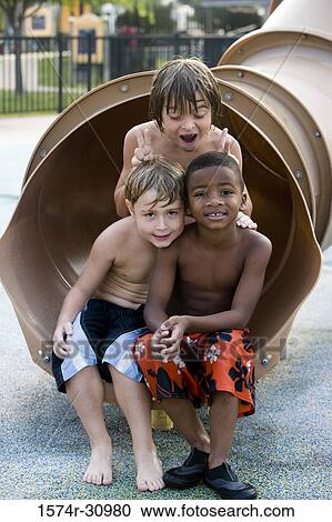 Stock Image - Portrait of boys sitting together at end of a slide. Fotosearch