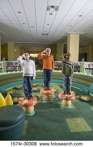 Portrait of boys standing on stools and saluting in the library View Large Photo Image Stock Photo - Portrait of boys standing on stools and saluting in the library. Fotosearch