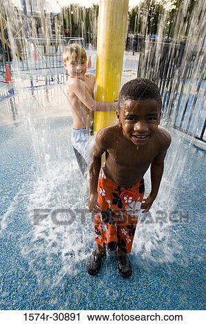 Stock Image - Portrait of boys standing under a shower. Fotosearch
