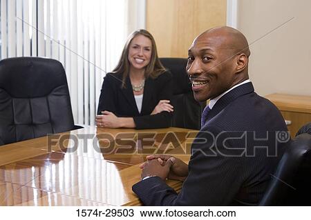 Stock Image - Portrait of business people in full suit smiling in an office. Fotosearch