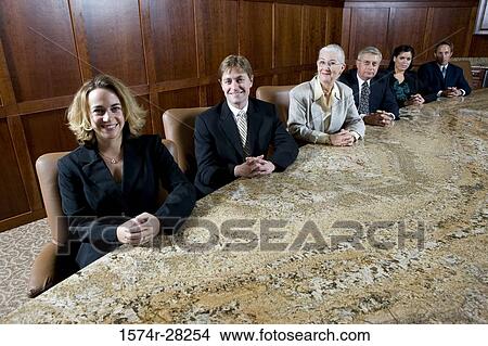 Portrait of business people sitting by conference table in an office View Large Photo Image Picture - Portrait of business people sitting by conference table in an office. Fotosearch