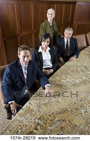 Portrait of business people sitting by conference table in an office View Large Photo Image Stock Photo - Portrait of business people sitting by conference table in an office. Fotosearch