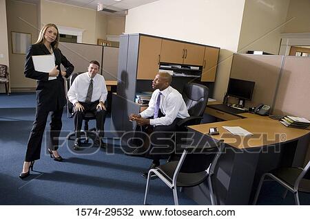 Stock Image - Portrait of businesswoman standing by colleagues in an office. Fotosearch