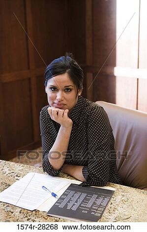 Portrait of businesswoman with hand on chin sitting by conference table in an office View Large Photo Image Stock Photo - Portrait of businesswoman with hand on chin sitting by conference table in an office. Fotosearch