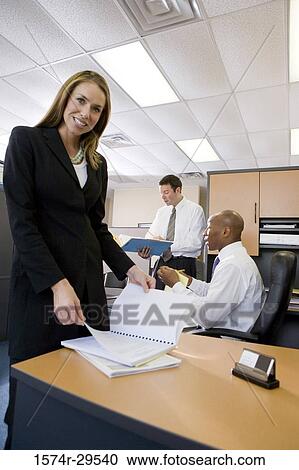 Stock Image - Portrait of businesswoman with colleagues in background. Fotosearch