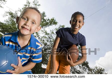 Portrait of cheerful children bending with footballs at park View Large Photo Image Stock Image - Portrait of cheerful children bending with footballs at park. Fotosearch