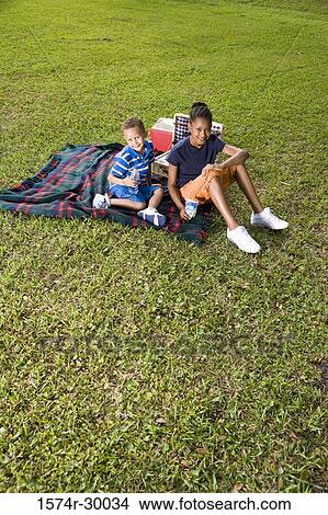 Portrait of cheerful children sitting on blanket at park View Large Photo Image Picture - Portrait of cheerful children sitting on blanket at park. Fotosearch