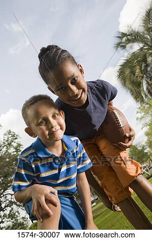 Portrait of cheerful children standing with football at park View Large Photo Image Stock Photo - Portrait of cheerful children standing with football at park. Fotosearch