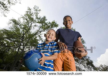 Portrait of cheerful children standing with footballs at park View Large Photo Image Stock Photo - Portrait of cheerful children standing with footballs at park. Fotosearch