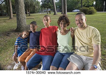 Portrait of cheerful family sitting on the bench at park View Large Photo Image Stock Image - Portrait of cheerful family sitting on the bench at park. Fotosearch
